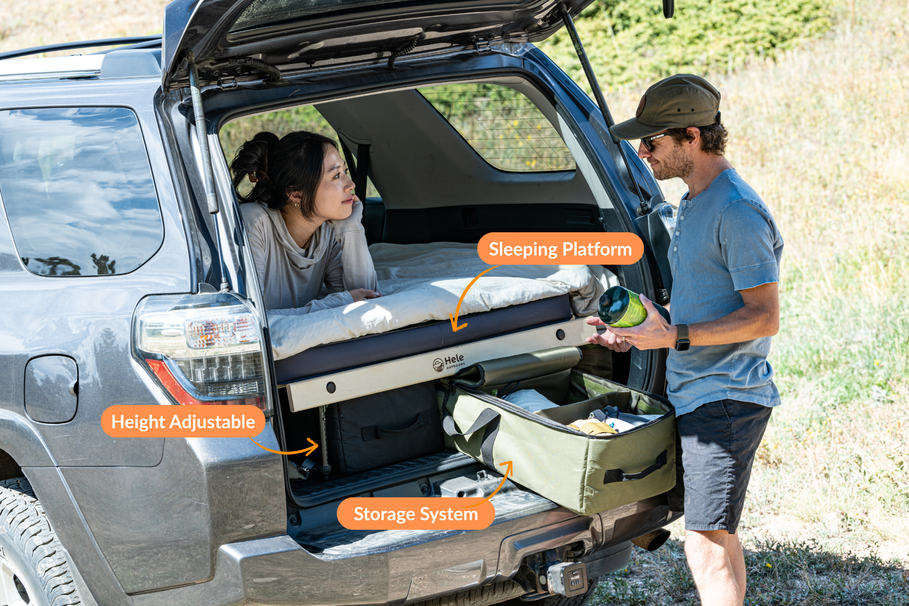 Two people interacting with a sleeping platform in the back of a vehicle, with labels indicating height adjustable and storage system features.