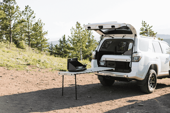 White SUV with open tailgate and camping setup in a natural setting